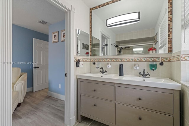 bathroom featuring hardwood / wood-style floors, vanity, a shower with door, and tile walls