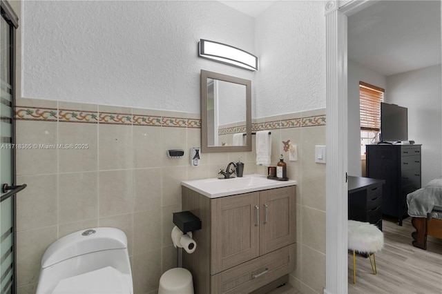 bathroom featuring vanity, toilet, and tile walls