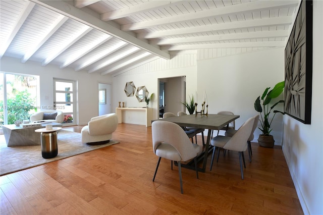 dining area with vaulted ceiling with beams and wood-type flooring