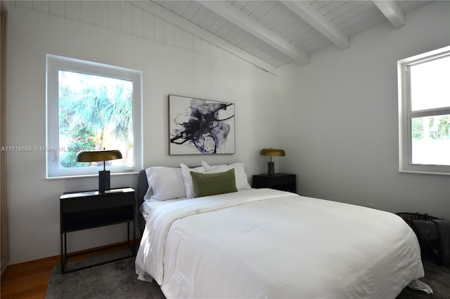 bedroom featuring multiple windows, beamed ceiling, and dark wood-type flooring