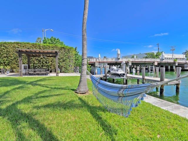 view of dock with a lawn and a water view