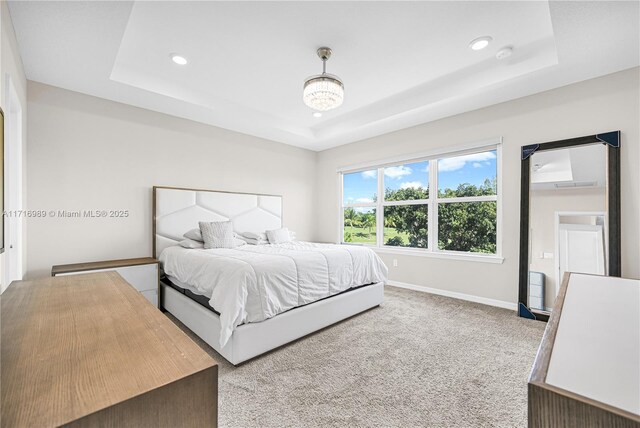 bedroom featuring light carpet, a tray ceiling, and ensuite bathroom