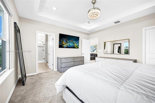 carpeted bedroom with connected bathroom and a raised ceiling