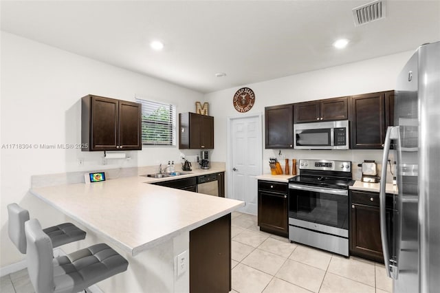 kitchen with a breakfast bar, light tile patterned flooring, kitchen peninsula, and stainless steel appliances