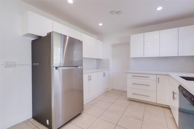 kitchen featuring stainless steel refrigerator, white cabinetry, dishwasher, decorative backsplash, and light tile patterned floors