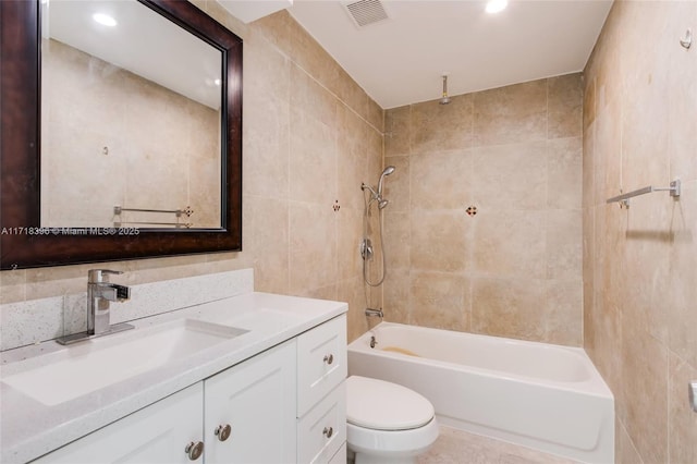 full bathroom with toilet, vanity, tile walls, and tiled shower / bath