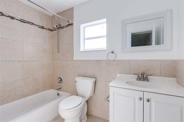 full bathroom featuring vanity, toilet, tiled shower / bath, and tile walls