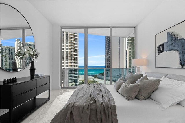 bedroom featuring access to outside, a wall of windows, a water view, and multiple windows