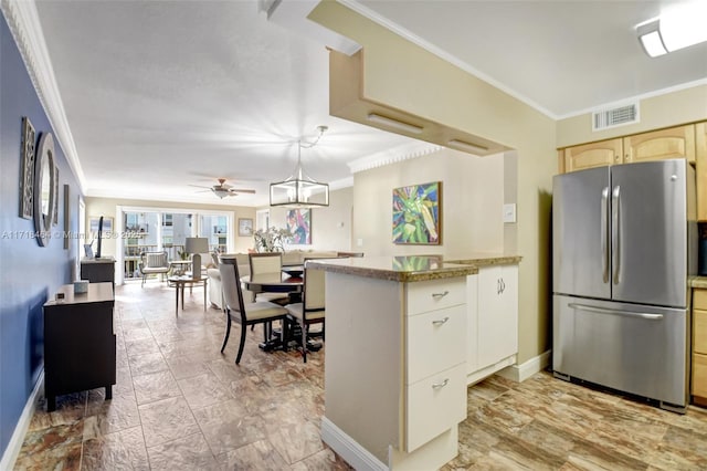 kitchen featuring ceiling fan, stainless steel fridge, crown molding, and hanging light fixtures