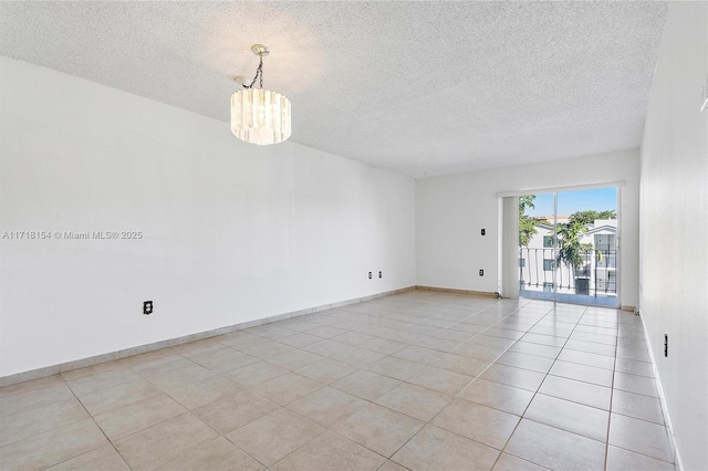 tiled empty room featuring a textured ceiling and an inviting chandelier