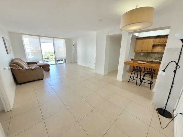 living room featuring expansive windows, light tile patterned flooring, and sink