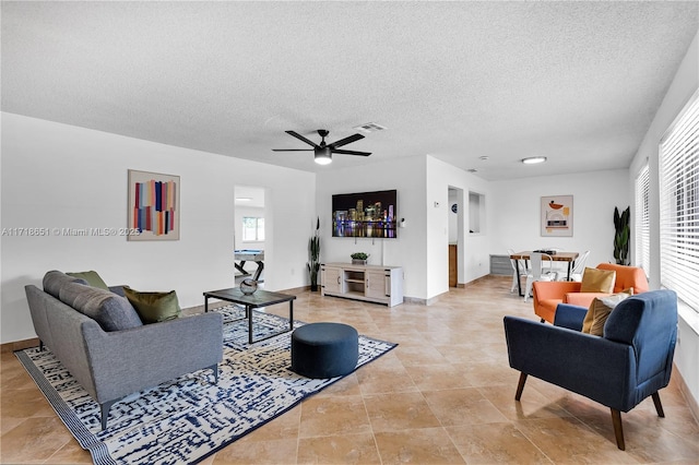 living room with ceiling fan, a wealth of natural light, and a textured ceiling