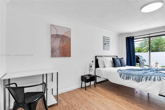 bedroom with ornamental molding, access to exterior, hardwood / wood-style floors, and a textured ceiling