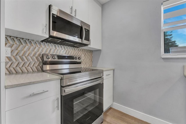 kitchen featuring stainless steel appliances, light stone countertops, light hardwood / wood-style flooring, and white cabinets