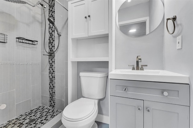 bathroom featuring vanity, a tile shower, and toilet