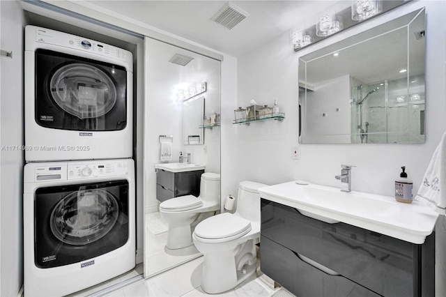 bathroom featuring vanity, toilet, a shower with door, and stacked washer / dryer