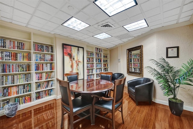 office area featuring a paneled ceiling, hardwood / wood-style flooring, and built in features