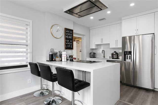 kitchen with a breakfast bar, white cabinets, sink, stainless steel refrigerator with ice dispenser, and kitchen peninsula