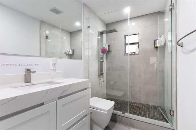 bathroom featuring vanity, toilet, and a shower with shower door