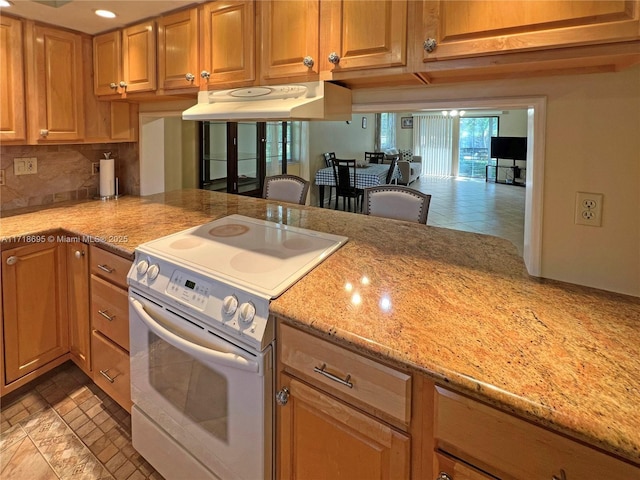 kitchen featuring decorative backsplash, light stone counters, and white electric range oven