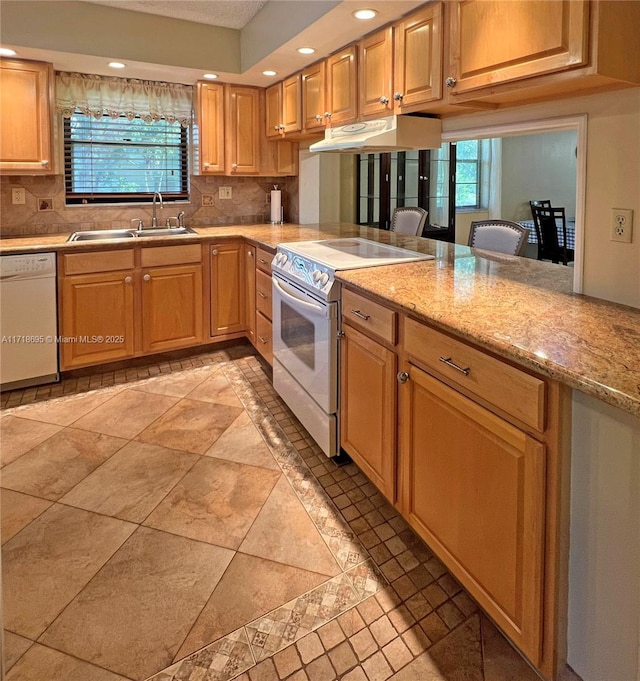 kitchen featuring decorative backsplash, plenty of natural light, light stone countertops, and white appliances