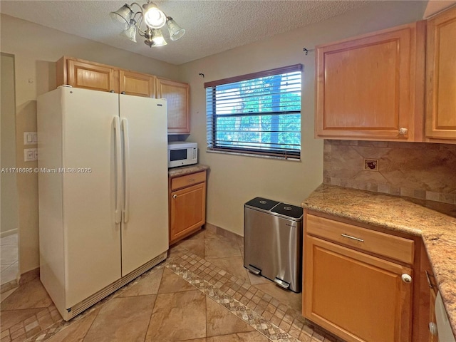 kitchen with decorative backsplash, light tile patterned flooring, white appliances, and a textured ceiling