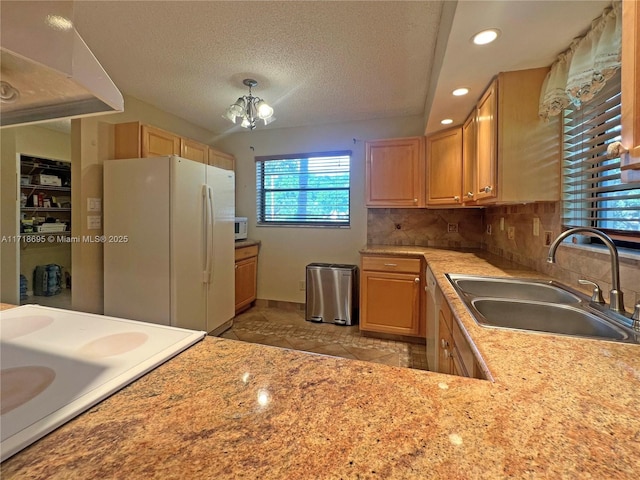 kitchen with sink, an inviting chandelier, a textured ceiling, white appliances, and decorative backsplash