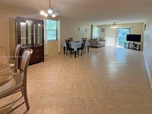 tiled dining area featuring ceiling fan with notable chandelier and a textured ceiling