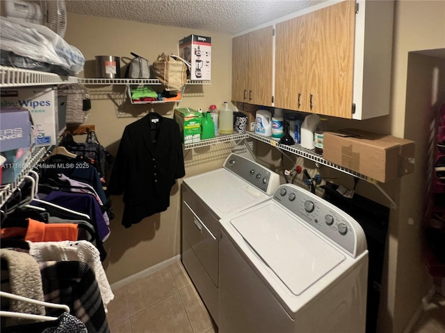 washroom with cabinets, light tile patterned floors, washer and dryer, and a textured ceiling