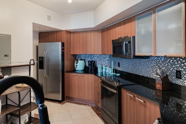 kitchen featuring decorative backsplash, light tile patterned flooring, stainless steel appliances, and dark stone counters