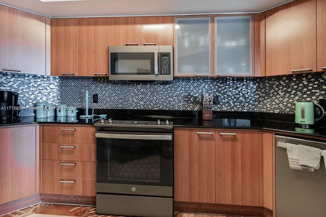 kitchen with decorative backsplash, dark stone countertops, and appliances with stainless steel finishes