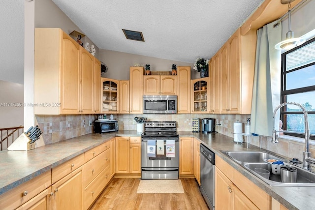 kitchen featuring light brown cabinets, sink, light wood-type flooring, a textured ceiling, and stainless steel appliances