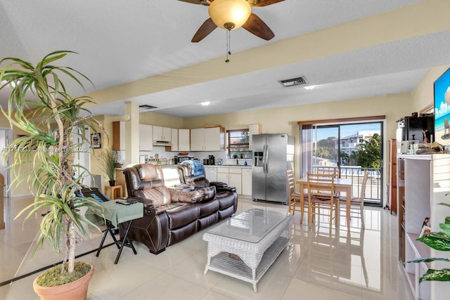 tiled living room featuring ceiling fan and a textured ceiling