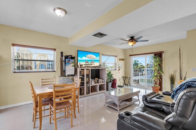 living room with ceiling fan, light tile patterned floors, and a textured ceiling