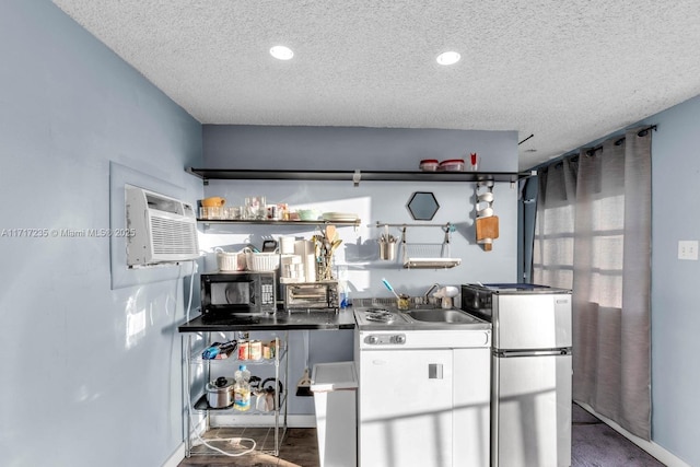 kitchen featuring a textured ceiling, a wall mounted AC, sink, white cabinetry, and fridge