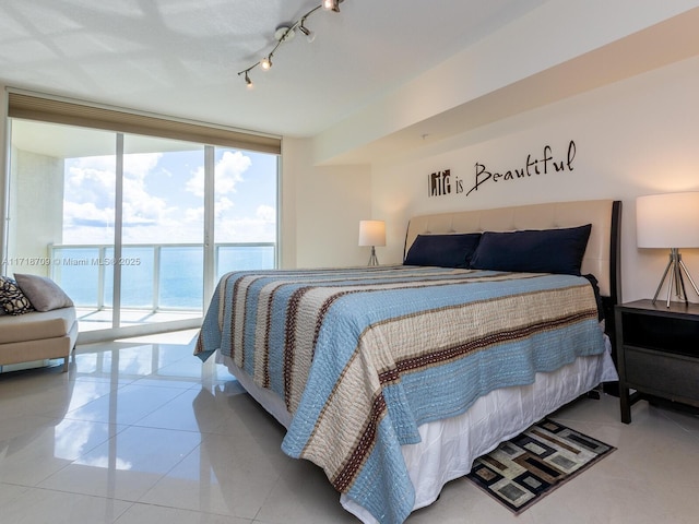 bedroom with access to exterior, a water view, a wall of windows, and light tile patterned floors