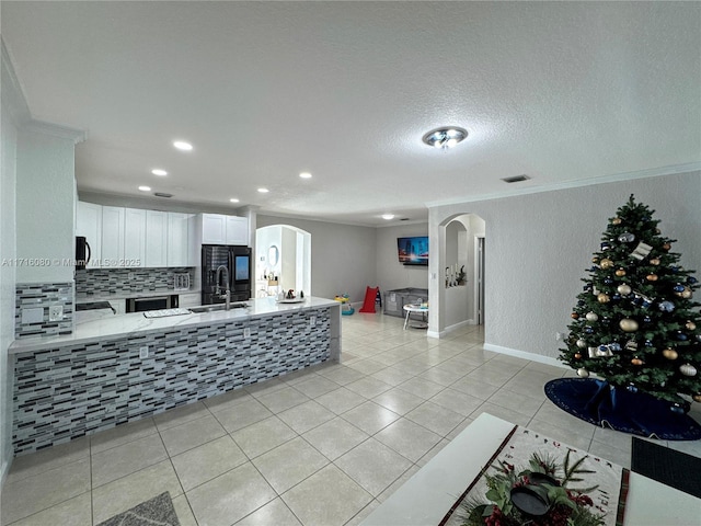 kitchen featuring backsplash, white cabinets, light tile patterned floors, a textured ceiling, and light stone counters