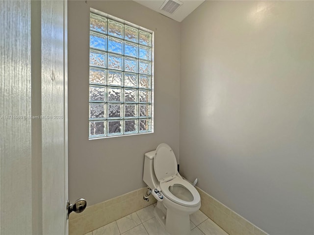 bathroom with toilet, tile patterned floors, and plenty of natural light