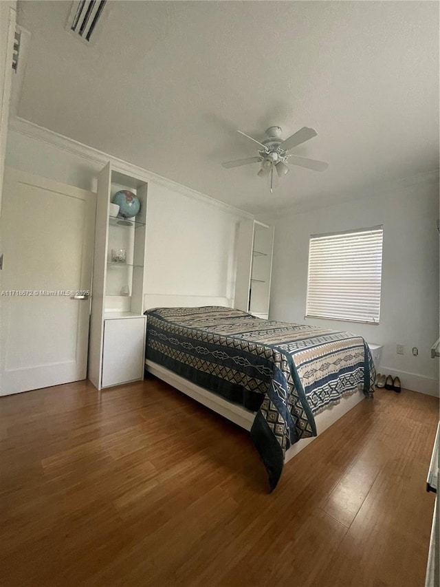 bedroom with crown molding, dark wood-type flooring, and ceiling fan