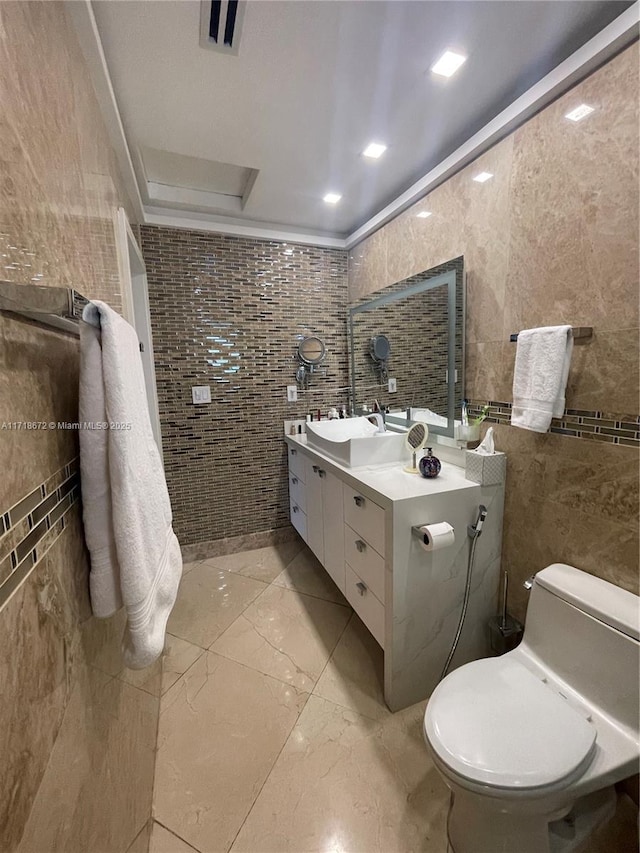 bathroom with vanity, tile walls, crown molding, and toilet