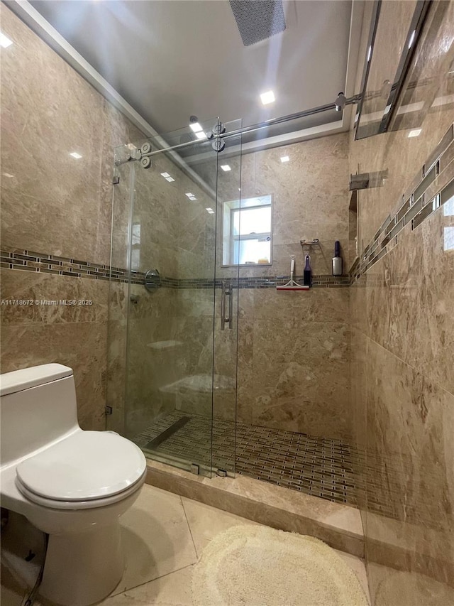 bathroom with a shower with shower door and toilet