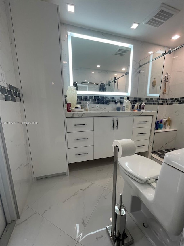 bathroom featuring vanity, tile walls, decorative backsplash, and a shower with shower door