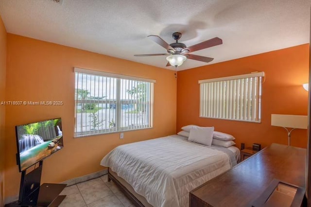 bedroom featuring ceiling fan, light tile patterned floors, and a textured ceiling