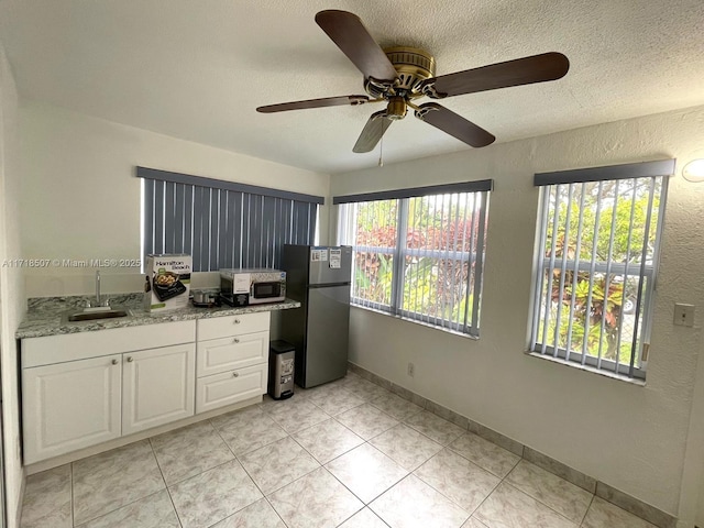 kitchen featuring white cabinetry, stainless steel refrigerator, plenty of natural light, and sink