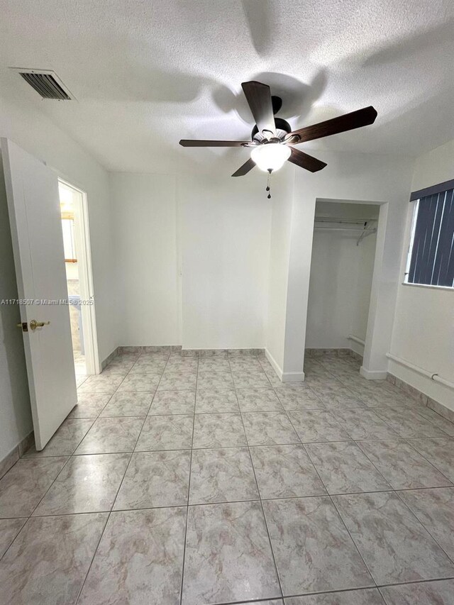 unfurnished bedroom featuring a textured ceiling, a closet, and ceiling fan