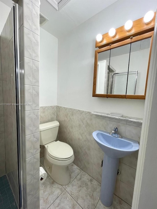 bathroom with a shower with door, tile walls, and toilet