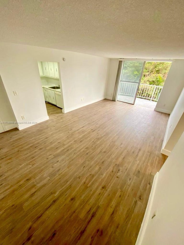 unfurnished room featuring sink, expansive windows, a textured ceiling, and light hardwood / wood-style flooring