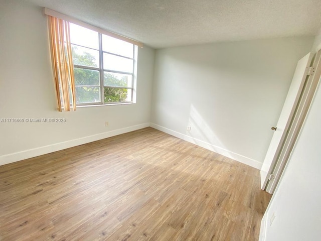 empty room with a textured ceiling and light hardwood / wood-style floors