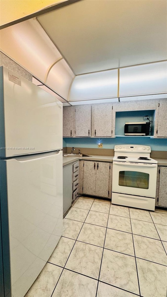 kitchen with white appliances, sink, and light tile patterned floors