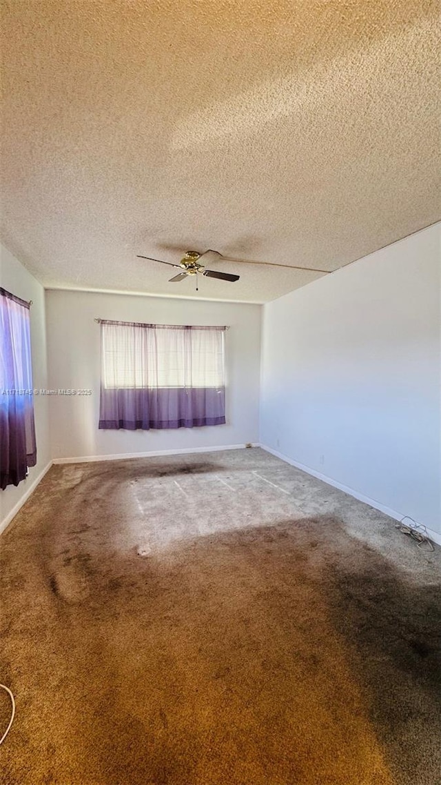 carpeted empty room with ceiling fan and a textured ceiling